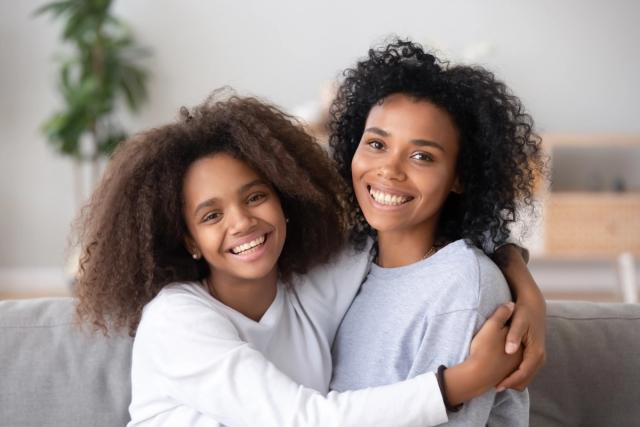 a mother and daughter are hugging each other while sitting on a couch .