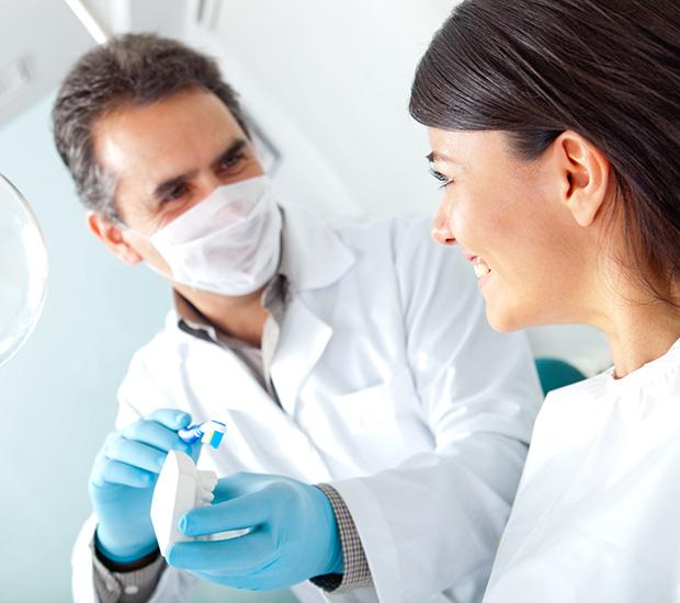 a dentist is giving a woman a toothbrush in a dental office .