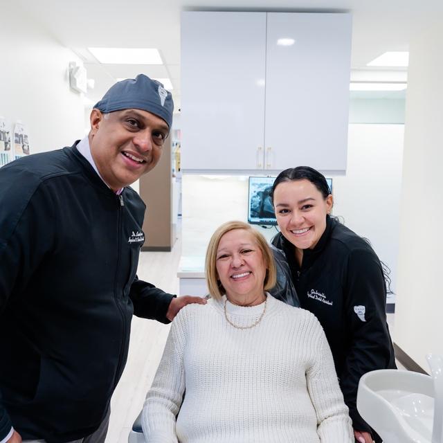 a man and two women are standing next to a woman in a dental chair .