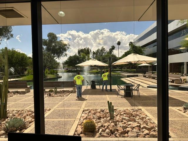 two men are standing under umbrellas in front of a fountain in a courtyard .