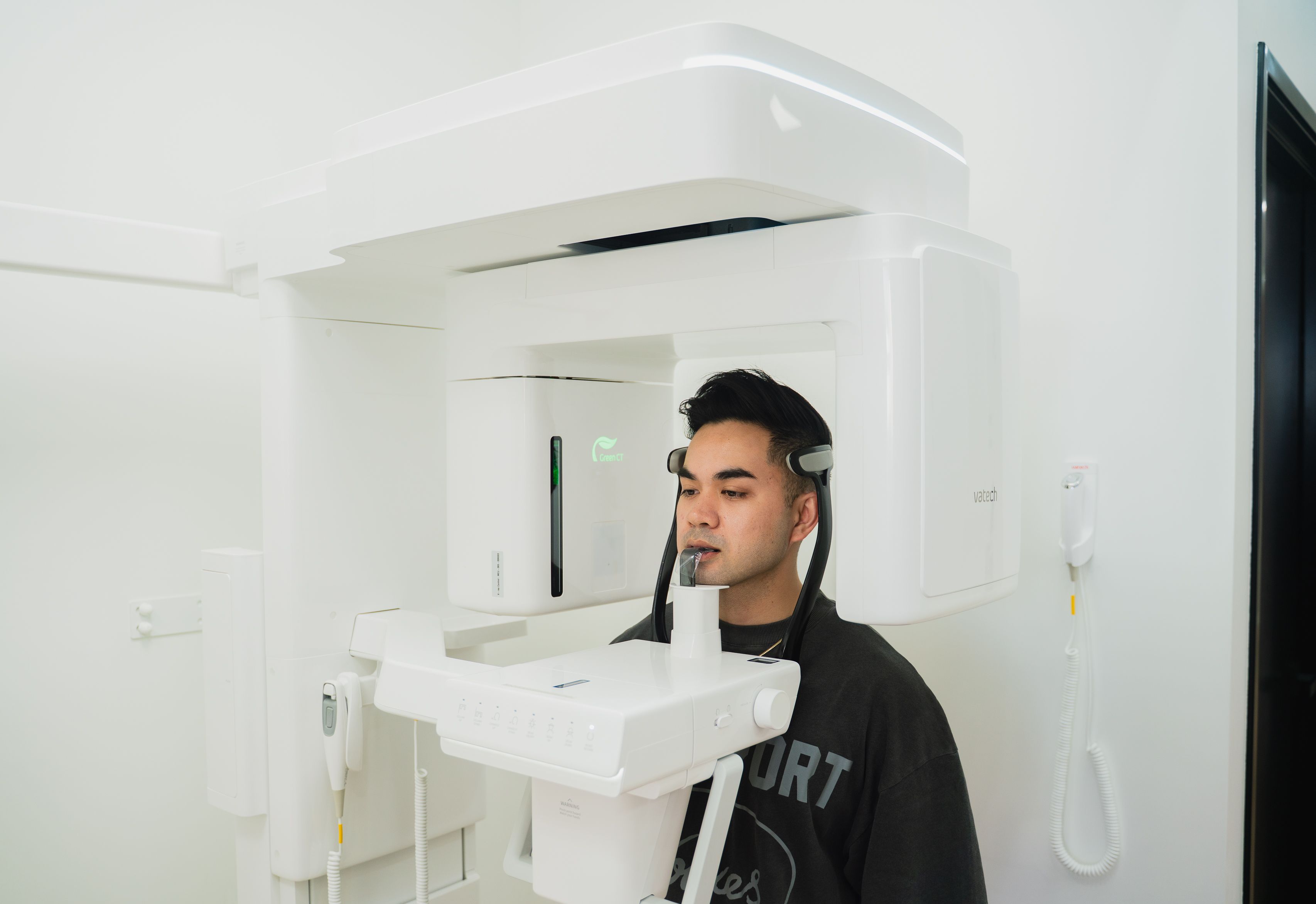 A man positioned in a modern dental panoramic X-ray machine.