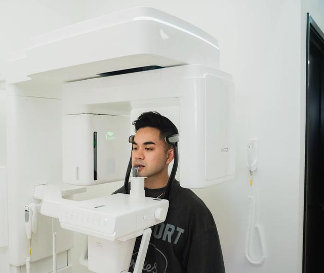 A man positioned in a modern dental panoramic X-ray machine.