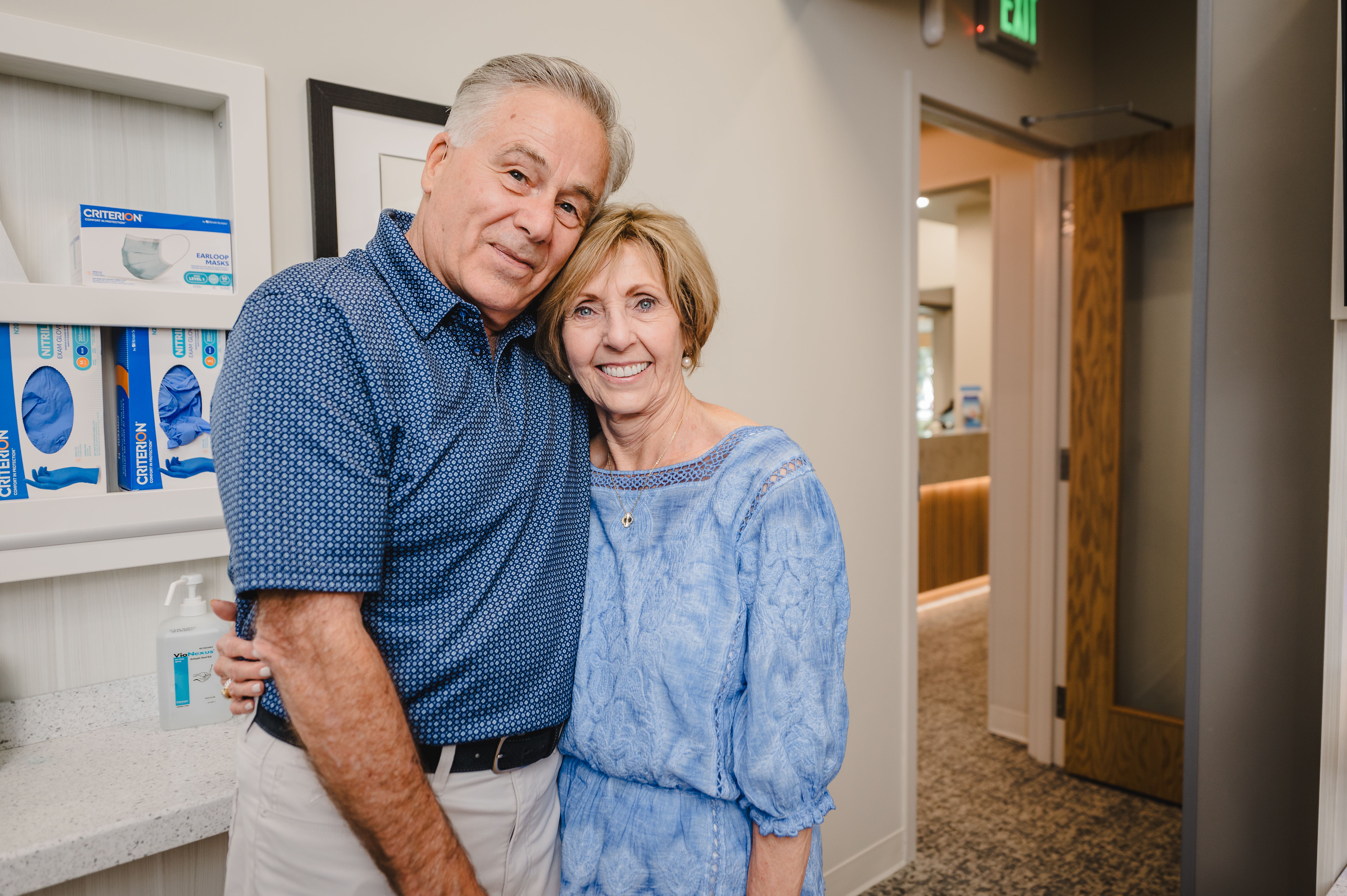 a man and woman are posing for a picture in front of a shelf with gloves on it .