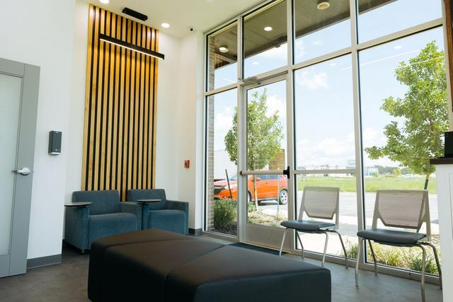 a waiting room with chairs , a bench , and a large window .