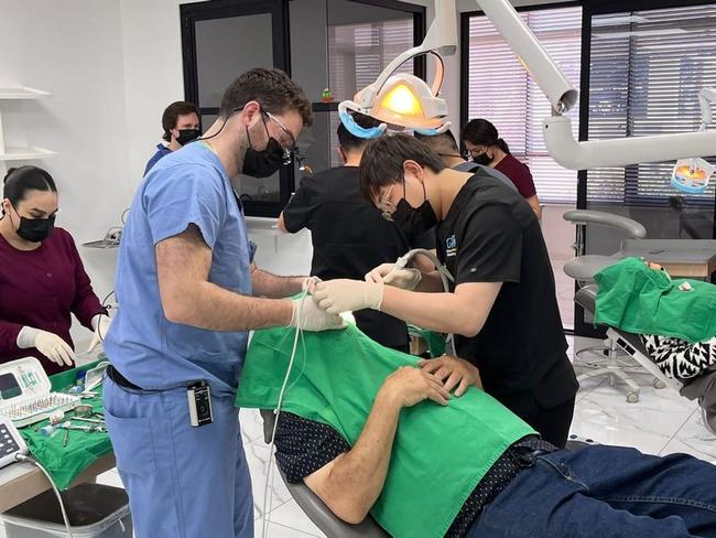 a group of dentists are working on a patient in a dental office .
