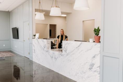 a woman is standing at a reception desk in a dental office .