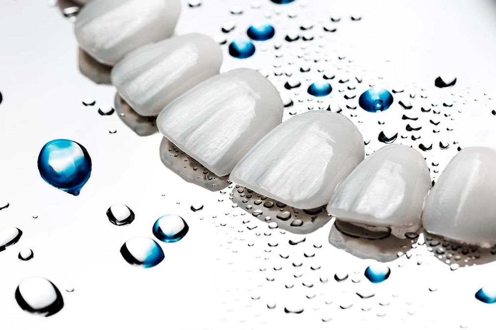 a close up of a row of white teeth with water drops on them .