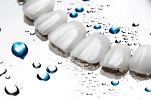 a close up of a row of white teeth with water drops on them .