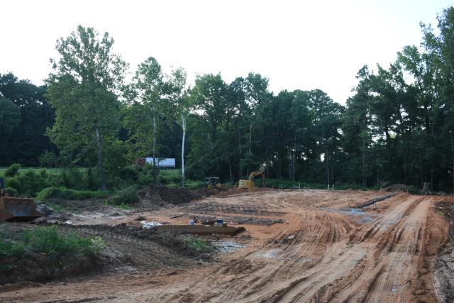 a construction site with a lot of dirt and trees in the background .