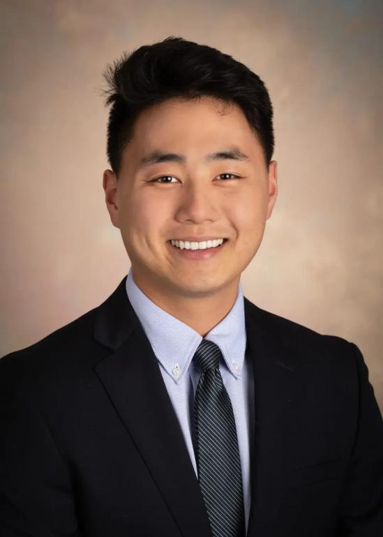 a young man in a suit and tie is smiling for the camera .