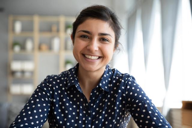 a woman in a polka dot shirt is smiling and looking at the camera .