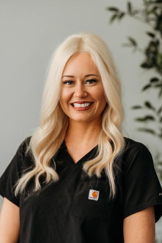 a woman in a black scrub top is smiling for the camera