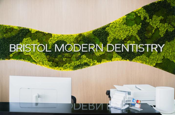 A modern dental office reception with a curved moss wall displaying "BRISTOL MODERN DENTISTRY".