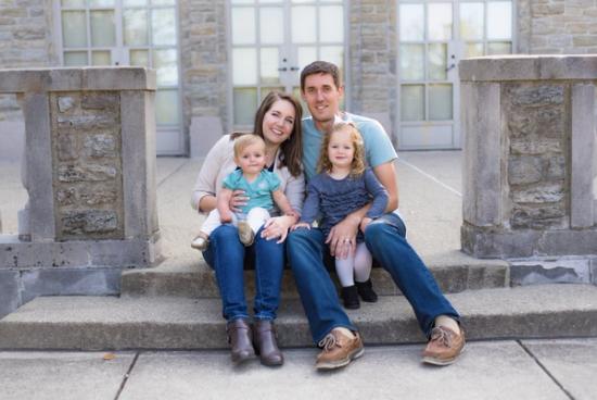 a family is sitting on the steps of a building .