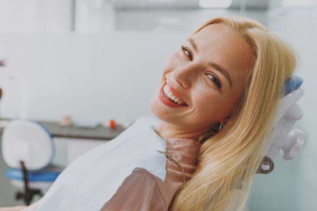 a woman is smiling while sitting in a dental chair .