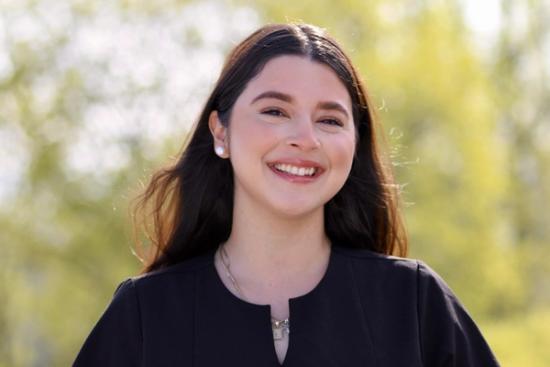 a woman in a black dress is smiling for the camera .
