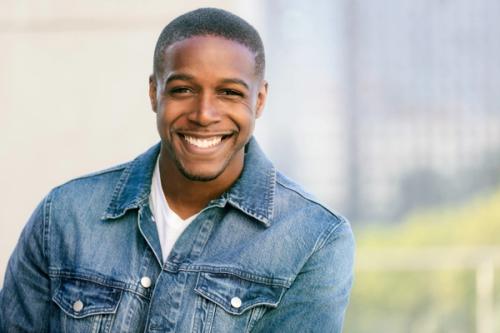 a young man in a denim jacket is smiling for the camera .
