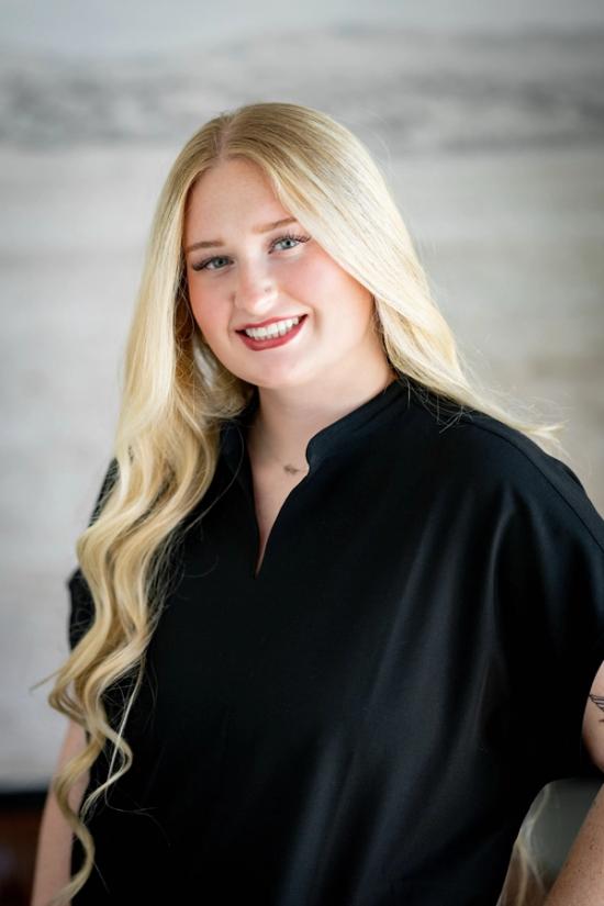 the woman is wearing a black shirt and smiling for the camera .