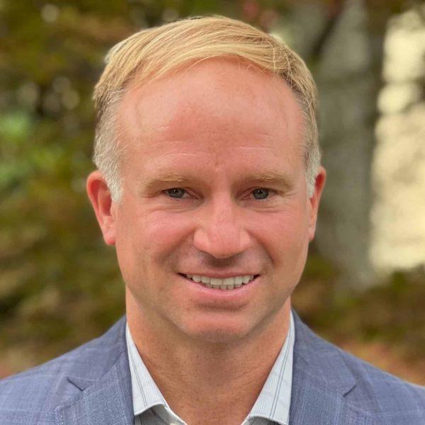 a man in a suit and tie is smiling for the camera .