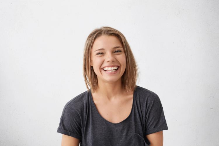 a young woman is laughing with her eyes closed and her mouth open .