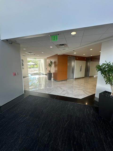 a hallway with a green exit sign on the ceiling
