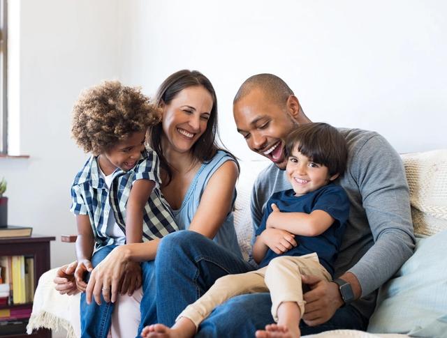 A happy family of four smiling and laughing together.