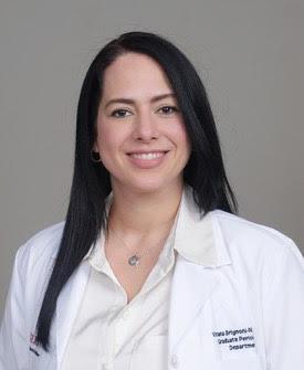 a woman in a white lab coat is smiling for the camera .