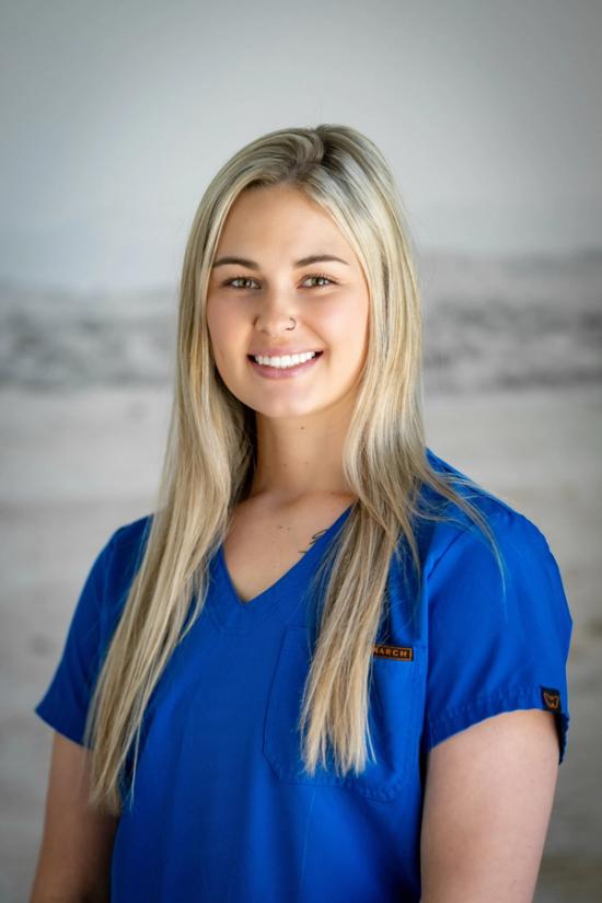 a woman wearing a blue scrub top with a name tag on it