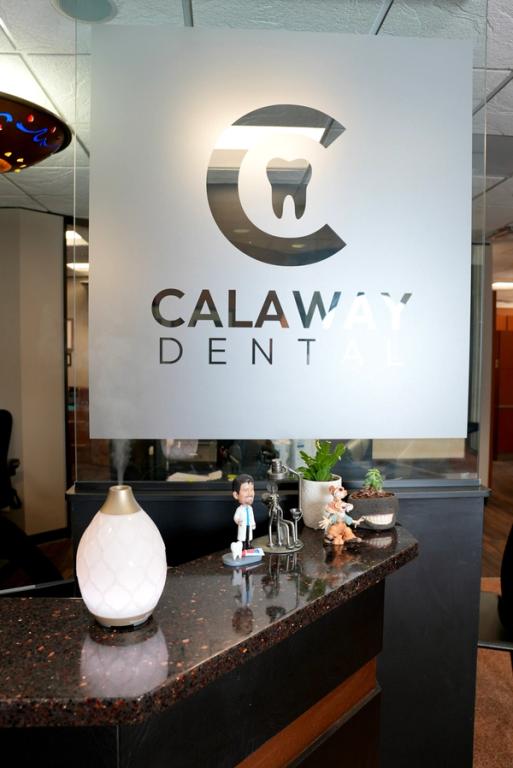 Calaway Dental logo on frosted glass above a reception counter with a diffuser and dental-themed decor.