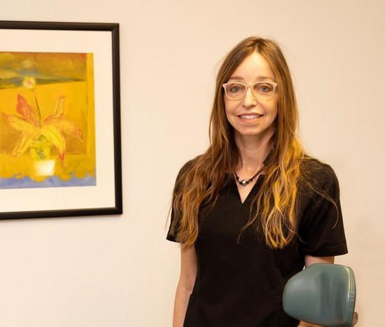 a woman in a black scrub is leaning on a dental chair