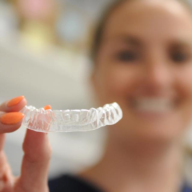 a woman is holding a clear brace in her hand .