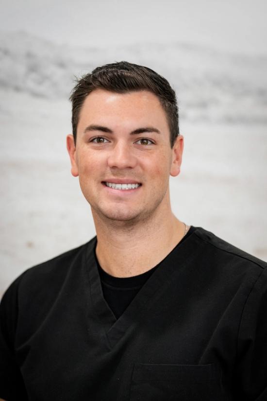 a man in a black scrub top is smiling for the camera .