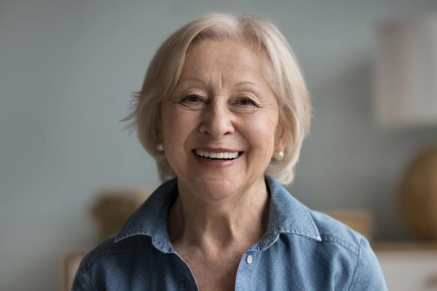 a close up of an elderly woman smiling for the camera .