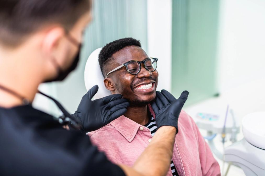 a man is sitting in a dental chair while a dentist examines his teeth .