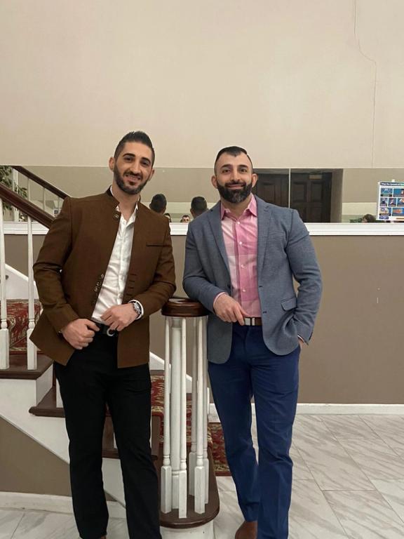 two men standing next to each other in front of stairs