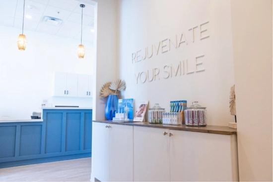 a dental office with a sign on the wall that says `` rejuvenate your smile '' .