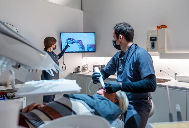 a dentist is examining a patient 's teeth in a dental office .