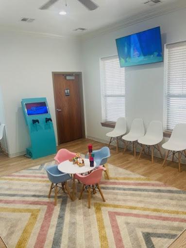 a waiting room with a table and chairs and a television .