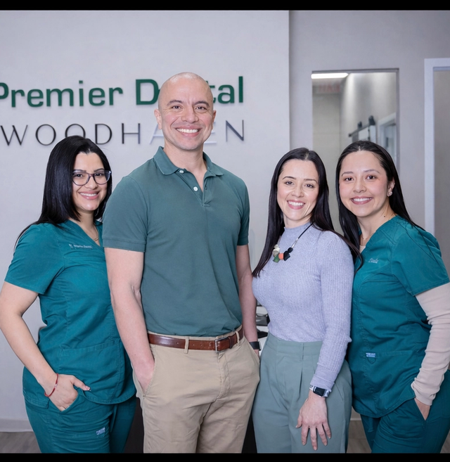 Four smiling dental staff members in front of the "Premier Dental of Woodhaven" sign.