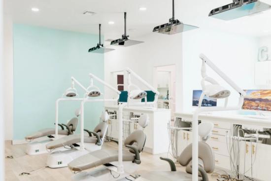 A clean and modern dental office with several empty patient chairs and equipment.