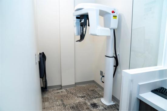 A white dental panoramic X-ray machine and a lead apron in a clinic room.