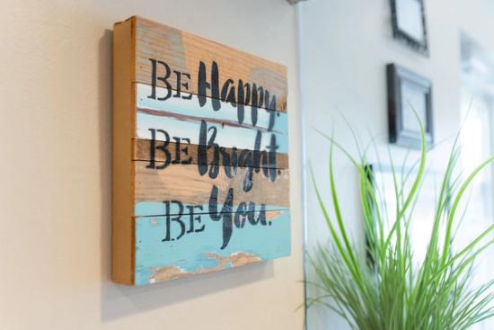 a wooden sign on a wall that says `` be happy be bright be you '' .