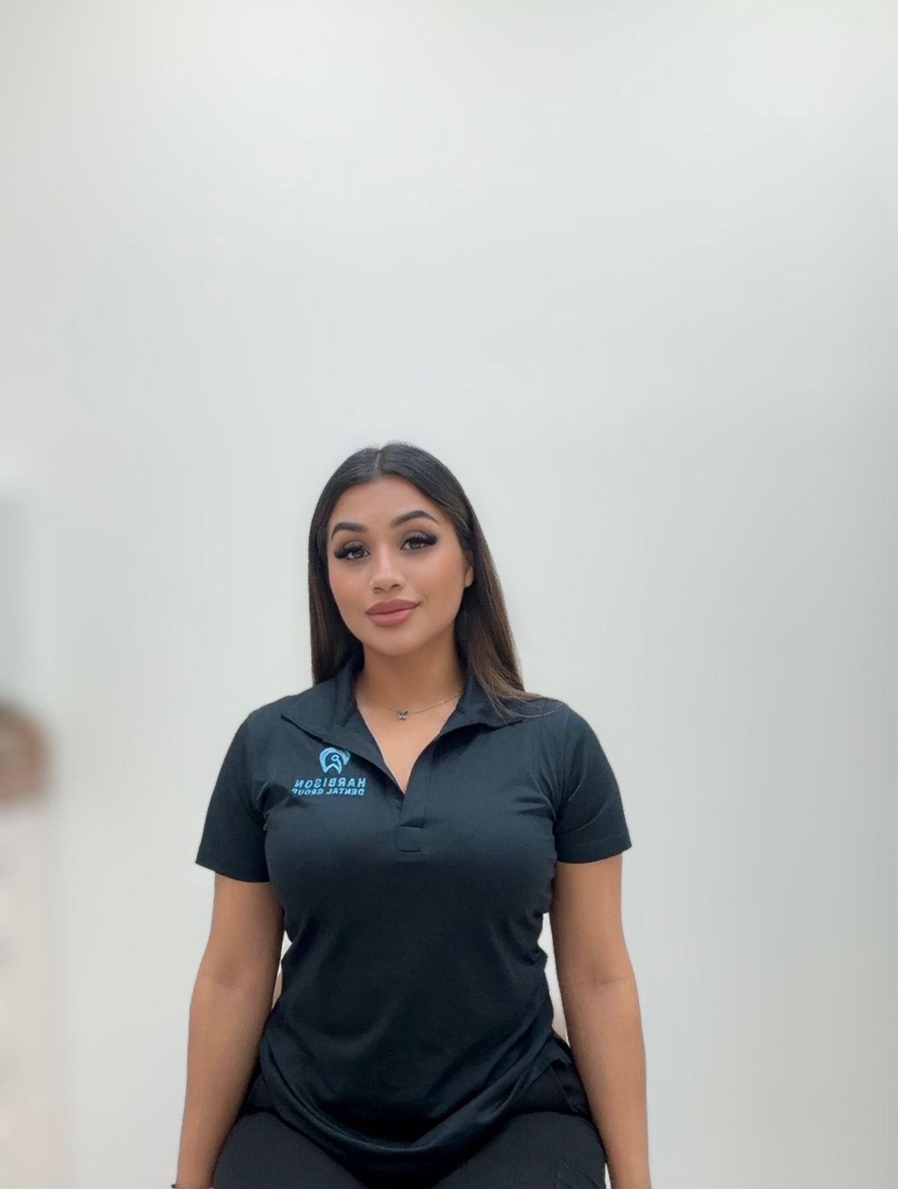 a woman is sitting on a chair wearing a black polo shirt .