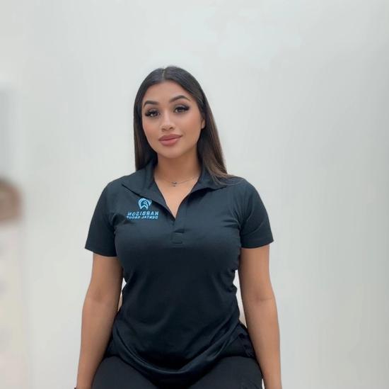 a woman is sitting on a chair wearing a black polo shirt .