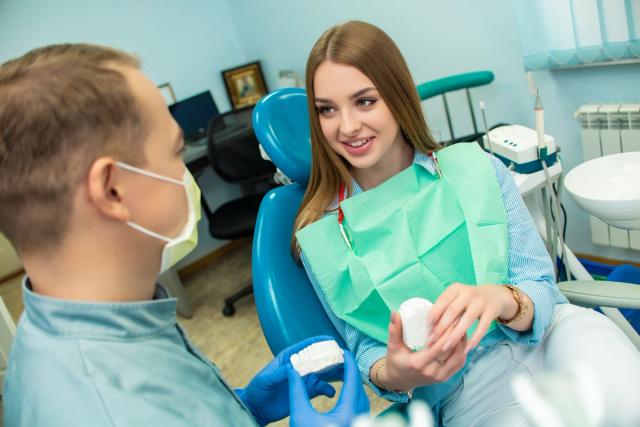a woman is sitting in a dental chair talking to a dentist .