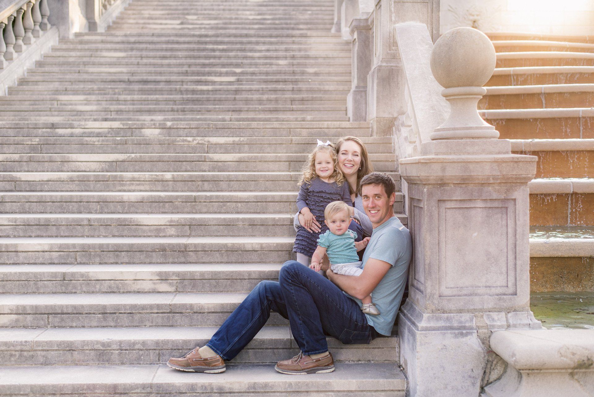 a family is sitting on the steps of a building .