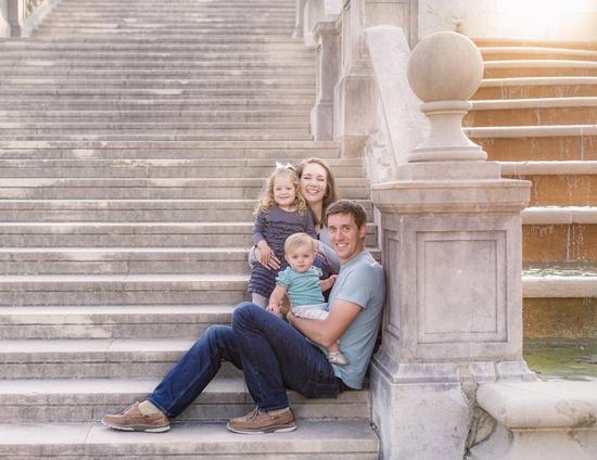 a family is sitting on the steps of a building .