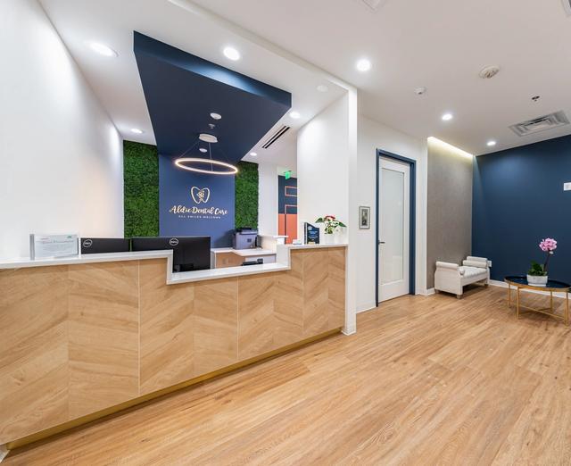 a dental office with a wooden reception desk and chairs .