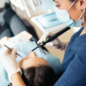 a dentist is using an electric toothbrush on a patient 's teeth .