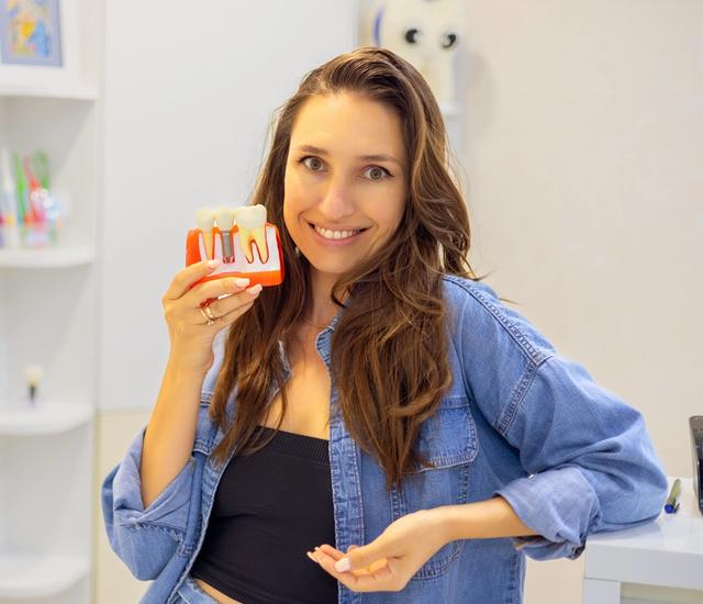 a woman is holding a model of her teeth and smiling .